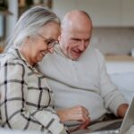 Couple using laptop together at home, looking into the true cost of homecare